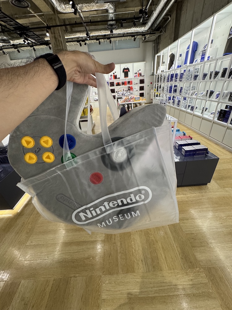 ニンテンドーミュージアムのショップでNINTENDO64コントローラクッションを買うところ